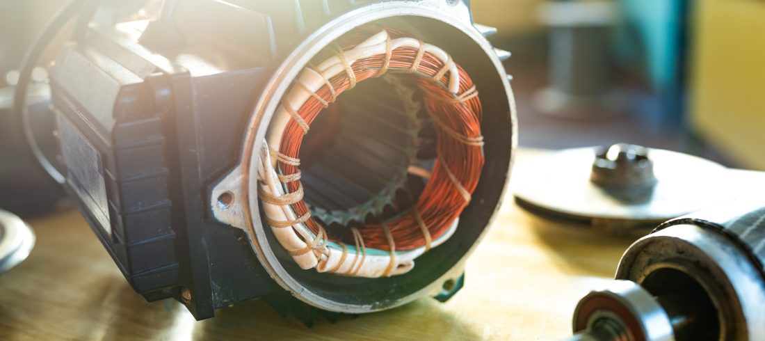 Close-up of iron industrial motor lies on a table 11Electric motor with exposed copper windings and removed components during a repair assessment.