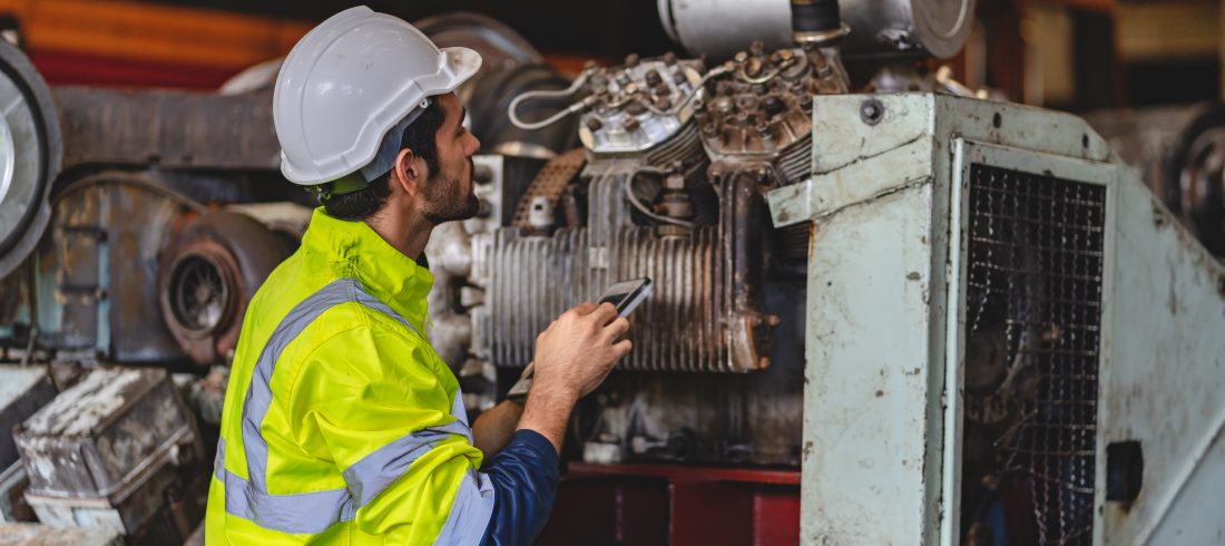 professional technician engineer with safety hard hat working to maintenance construction 11Engineer inspecting heavy industrial machinery while assessing the need for Predictive Maintenance Services.