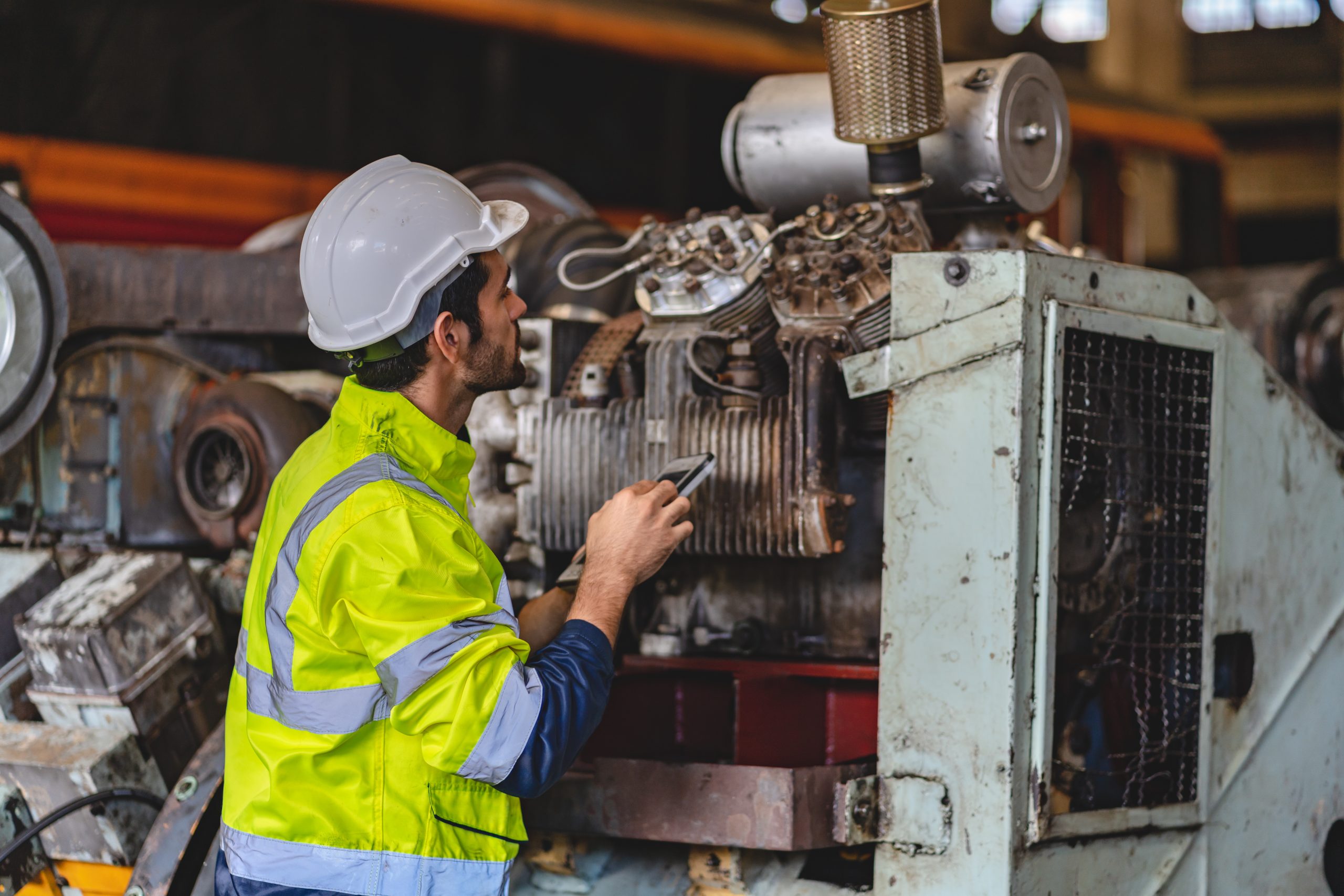 professional technician engineer with safety hard hat working to maintenance construction 11Engineer inspecting heavy industrial machinery while assessing the need for Predictive Maintenance Services.